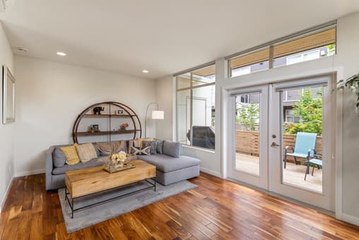 Elegant lounge with wood flooring, angular grey furniture, and grey roller blinds to match.
